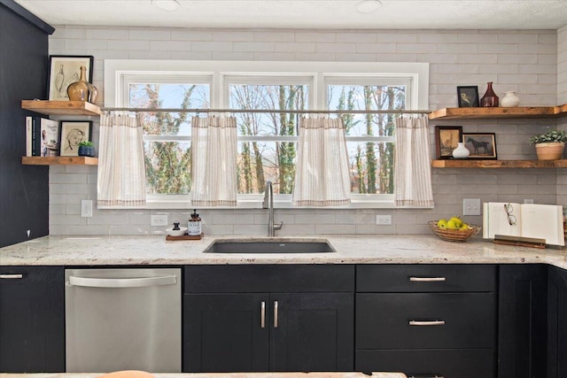 kitchen featuring open shelves, dark cabinets, dishwasher, decorative backsplash, and a sink