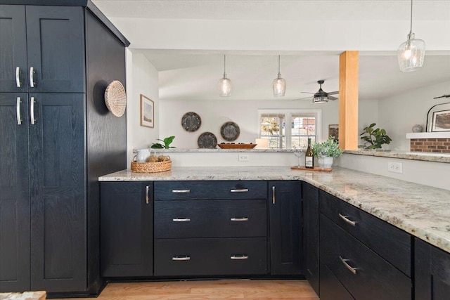 kitchen featuring hanging light fixtures, light stone counters, and ceiling fan