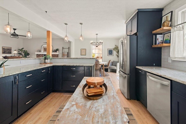 kitchen featuring stainless steel appliances, tasteful backsplash, an inviting chandelier, and light wood-style flooring