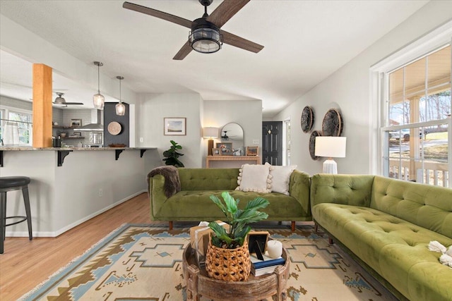 living area featuring a wealth of natural light, baseboards, wood finished floors, and a ceiling fan