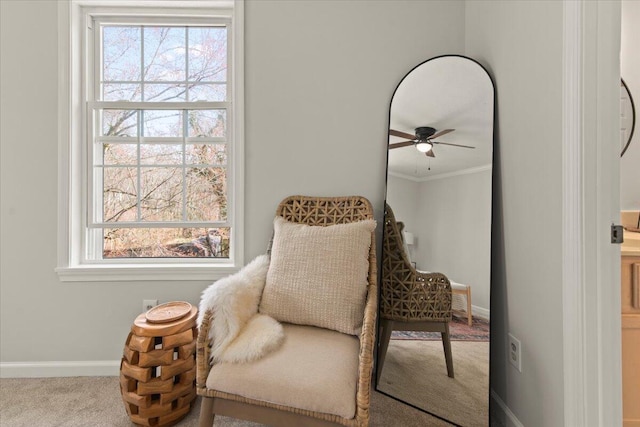 sitting room with baseboards, crown molding, carpet, and a ceiling fan