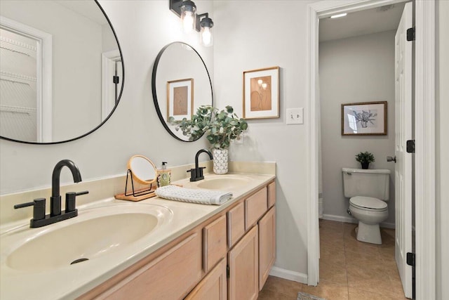 bathroom featuring tile patterned flooring, double vanity, toilet, and a sink