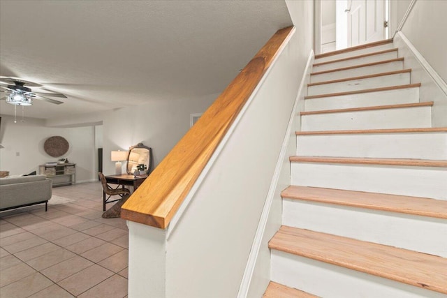 stairs with tile patterned floors and a ceiling fan