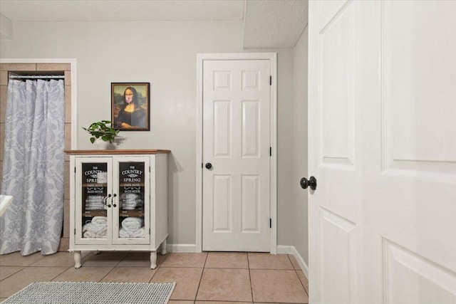 interior space featuring light tile patterned flooring, baseboards, and a textured ceiling