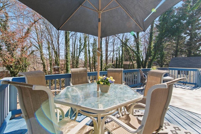 deck featuring outdoor dining space, an outdoor structure, and a storage unit