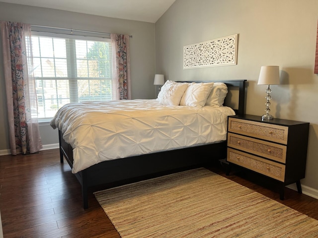 bedroom with vaulted ceiling, multiple windows, wood finished floors, and baseboards