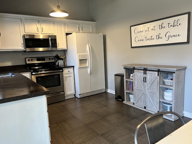 kitchen with dark countertops, white cabinets, baseboards, and stainless steel appliances