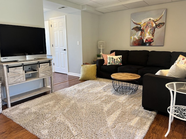 living area featuring visible vents, a paneled ceiling, baseboards, and wood finished floors