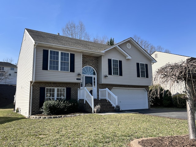 split foyer home featuring aphalt driveway, brick siding, an attached garage, and a front lawn