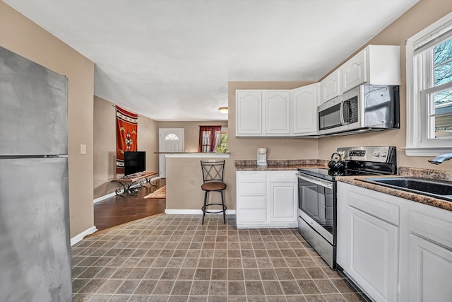 kitchen featuring white cabinetry, plenty of natural light, baseboards, and appliances with stainless steel finishes