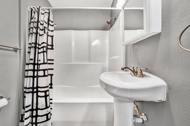 bathroom with a shower with shower curtain and a textured wall