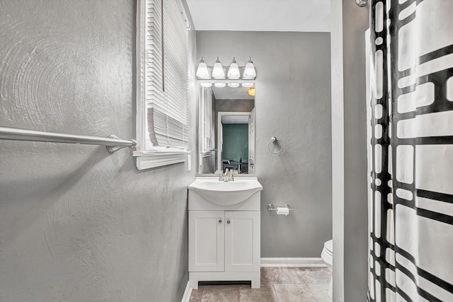 bathroom with toilet, a shower with shower curtain, baseboards, vanity, and a textured wall