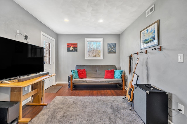 living room featuring visible vents, baseboards, and wood finished floors