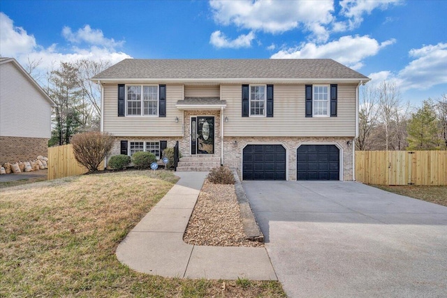 bi-level home featuring a front lawn, an attached garage, driveway, and fence