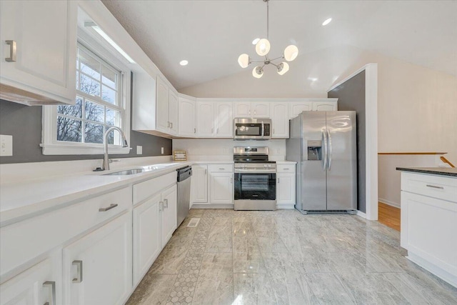 kitchen with a sink, lofted ceiling, appliances with stainless steel finishes, and white cabinets