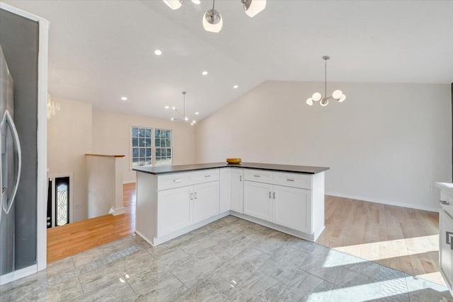 kitchen with dark countertops, light wood-type flooring, lofted ceiling, a notable chandelier, and white cabinetry