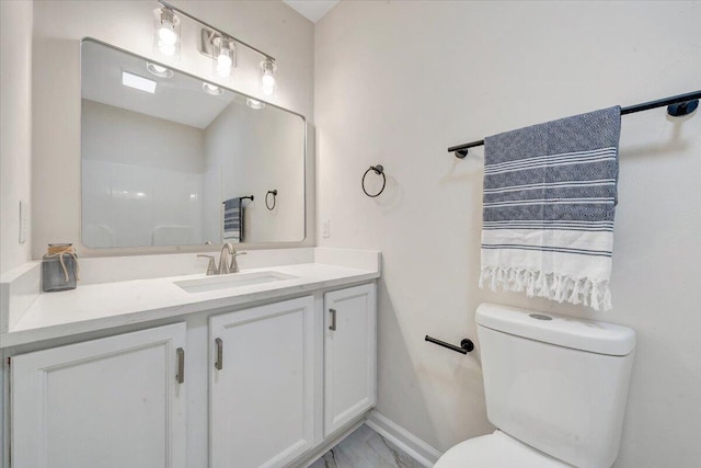 bathroom featuring vanity, toilet, baseboards, and marble finish floor