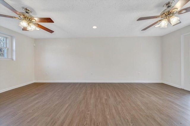 spare room featuring baseboards, a textured ceiling, and wood finished floors