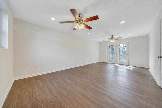 empty room with recessed lighting, wood finished floors, baseboards, and a textured ceiling