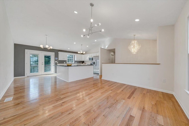 unfurnished living room with french doors, a chandelier, vaulted ceiling, and light wood finished floors