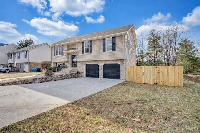 bi-level home featuring a garage, fence, brick siding, and driveway