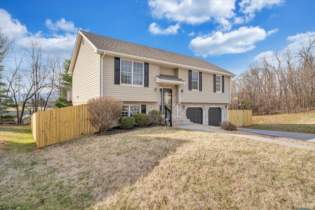 bi-level home with a front lawn, fence, an attached garage, a shingled roof, and brick siding