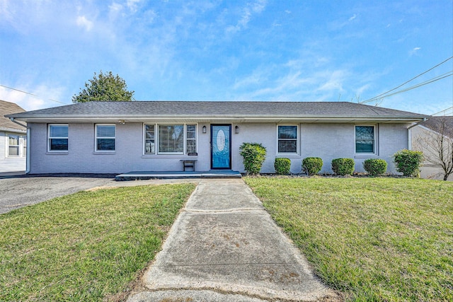 ranch-style house with brick siding, roof with shingles, and a front yard