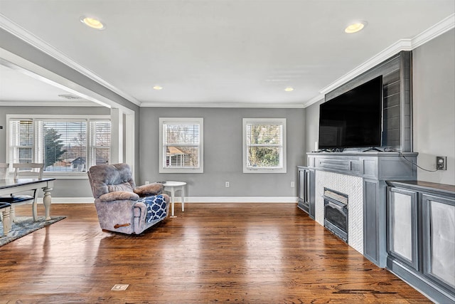 sitting room with a tiled fireplace, crown molding, dark wood-style floors, and baseboards