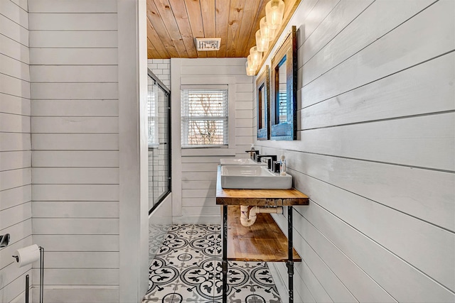 full bath with visible vents, bath / shower combo with glass door, wood walls, wooden ceiling, and tile patterned floors