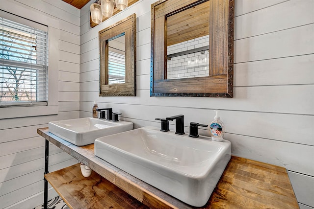 bathroom featuring wooden walls and a sink