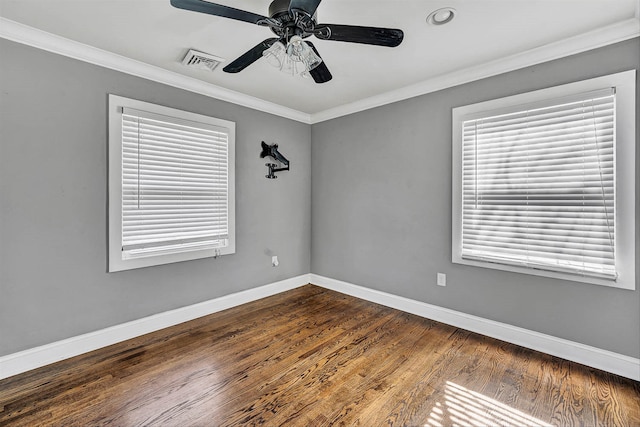 unfurnished room featuring dark wood-style floors, visible vents, crown molding, and baseboards