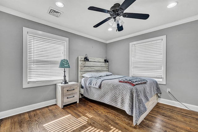 bedroom with wood finished floors, crown molding, baseboards, and visible vents