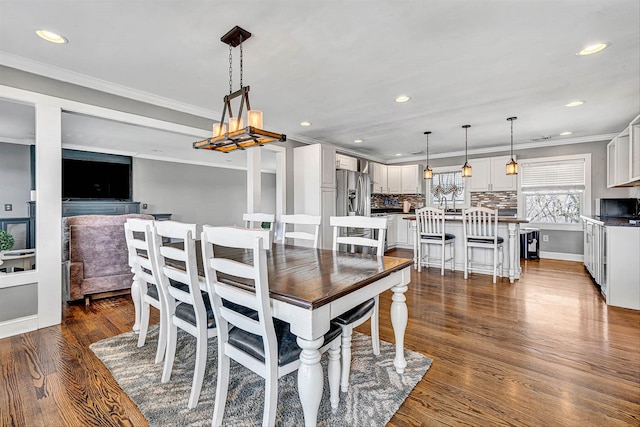 dining room with dark wood-style floors, a chandelier, recessed lighting, and crown molding