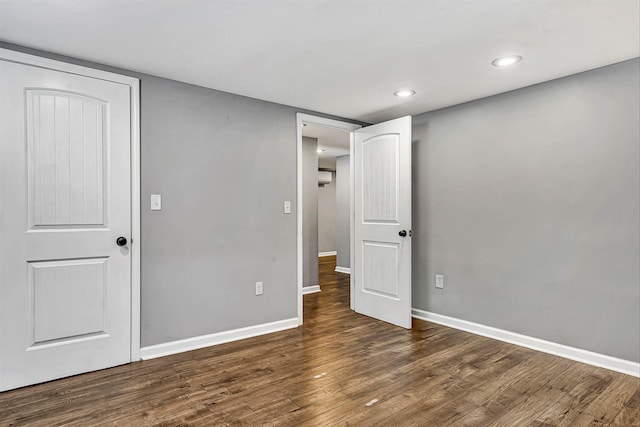 unfurnished bedroom with recessed lighting, baseboards, a wall mounted air conditioner, and dark wood-style flooring