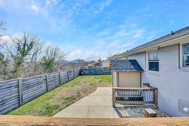 view of yard with a shed, a fenced backyard, an outbuilding, a mountain view, and a patio