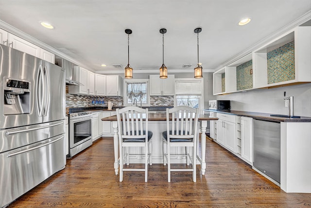 kitchen with dark wood-style floors, open shelves, decorative backsplash, appliances with stainless steel finishes, and dark countertops