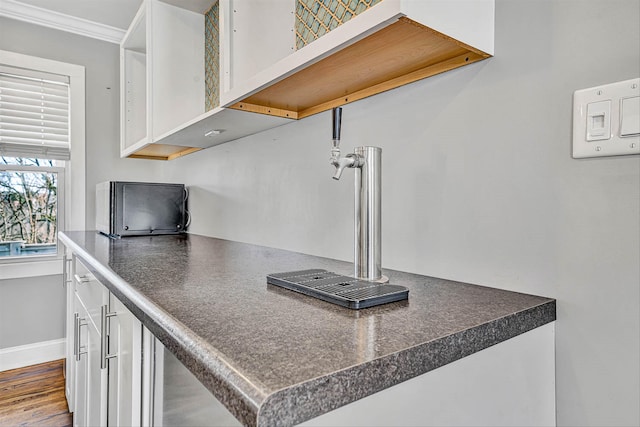 kitchen with ornamental molding, open shelves, dark countertops, white cabinets, and baseboards