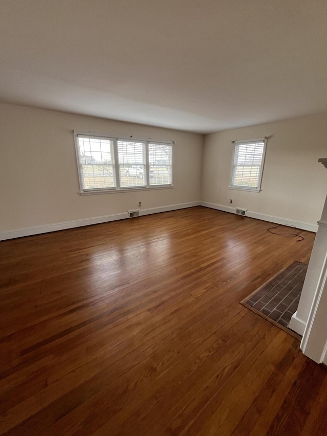 unfurnished room with visible vents, baseboards, and dark wood-style flooring