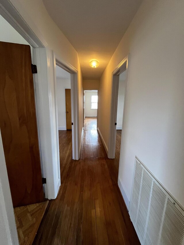 hallway featuring dark wood-style floors, visible vents, and baseboards