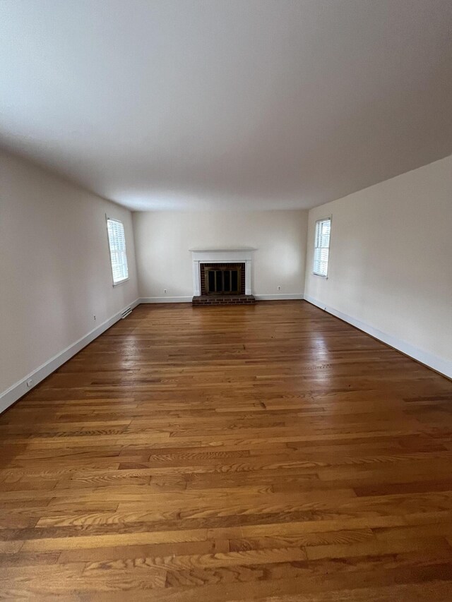 unfurnished living room featuring a fireplace, baseboards, and wood finished floors