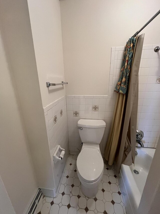 bathroom with wainscoting, toilet, tile walls, and shower / tub combo with curtain