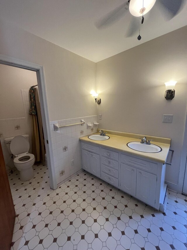 bathroom with a sink, toilet, tile walls, and double vanity