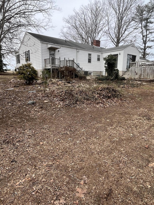 back of house featuring a chimney and a wooden deck