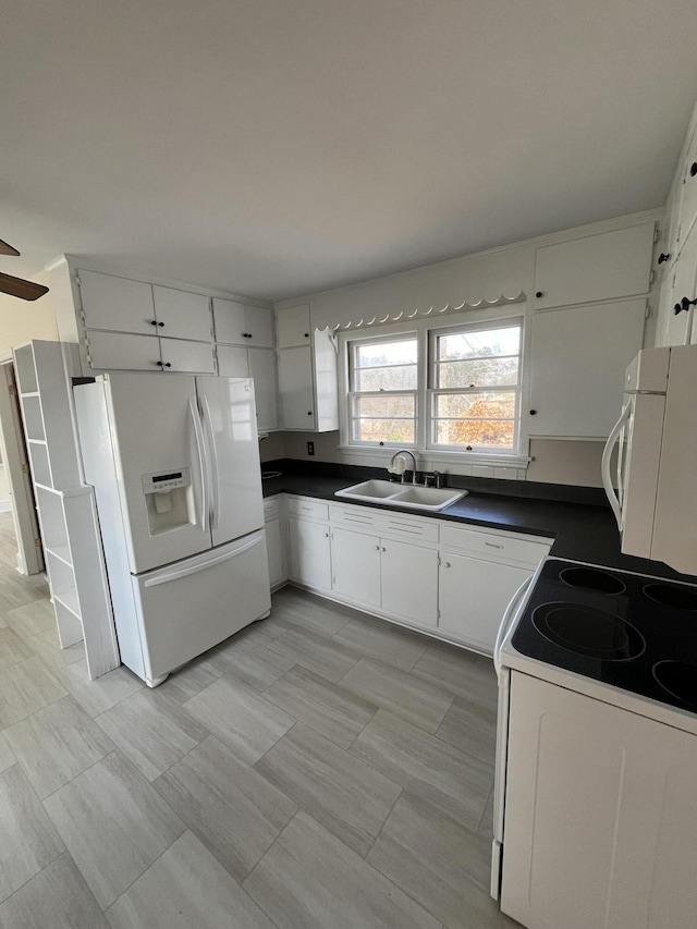 kitchen featuring white appliances, white cabinets, dark countertops, and a sink