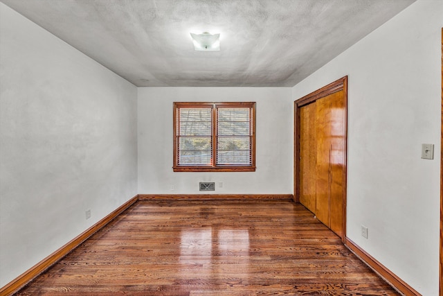 spare room featuring visible vents, baseboards, and wood finished floors