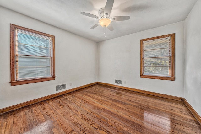 unfurnished room featuring visible vents, plenty of natural light, and wood finished floors