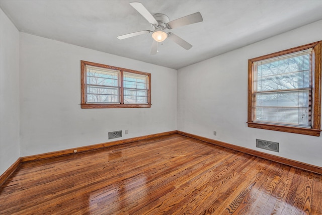 unfurnished room featuring visible vents, plenty of natural light, and wood finished floors