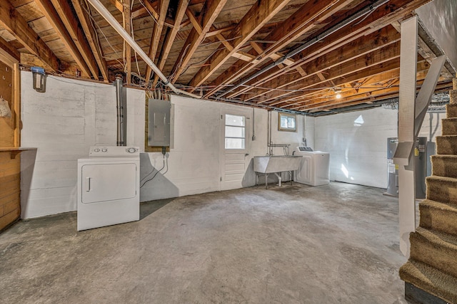 below grade area featuring electric panel, a sink, washing machine and dryer, water heater, and stairway