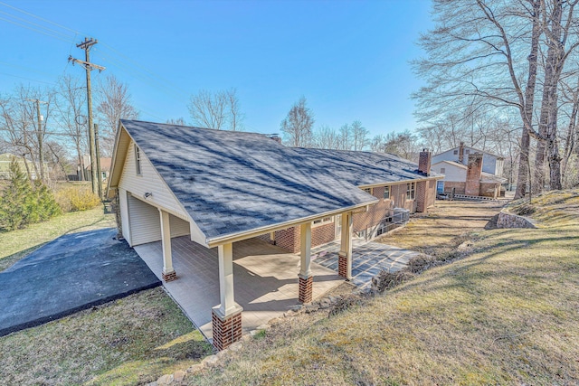 exterior space featuring a lawn and a shingled roof