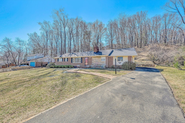 single story home with aphalt driveway, brick siding, a chimney, and a front yard